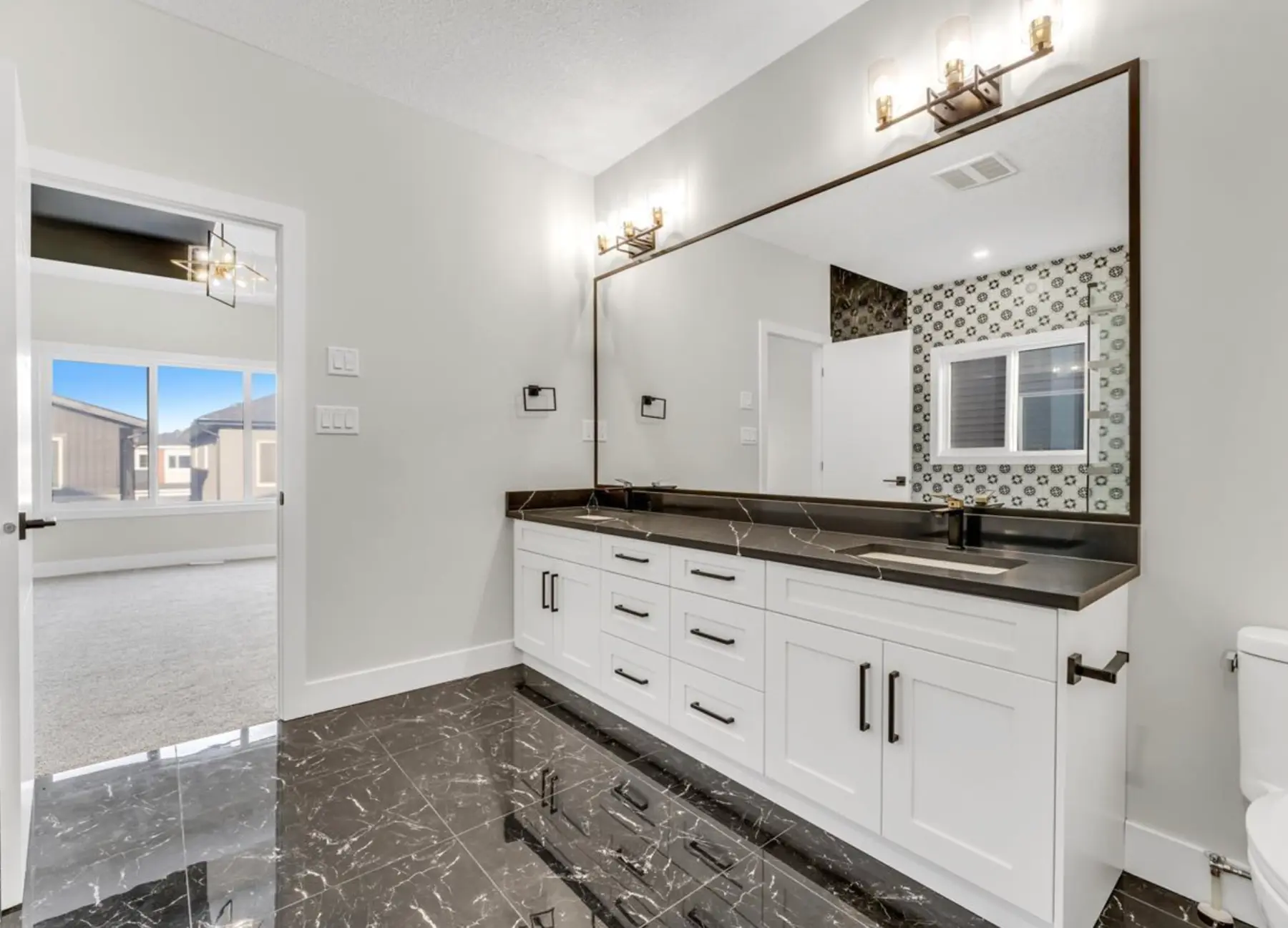 Primary ensuite with an extended double vanity and black stone finishes in the Laurel residence